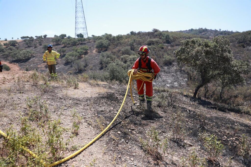 Imagen aérea de un incendio forestal en una zona rural de Huelva, con llamas y humo en el horizonte